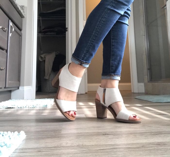 A reviewer modeling open-toe, high-heeled sandals featuring ankle straps