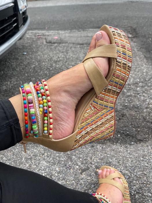 A close-up of beige wedges on a reviewer’s feet