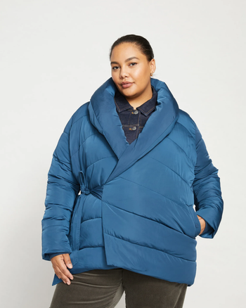 Person wearing a chic blue oversized puffer coat with a wrap design and a large collar, perfect for winter fashion