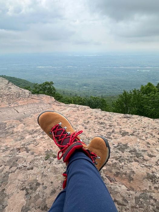 A reviewer showcasing tan hiking boots with vibrant red laces