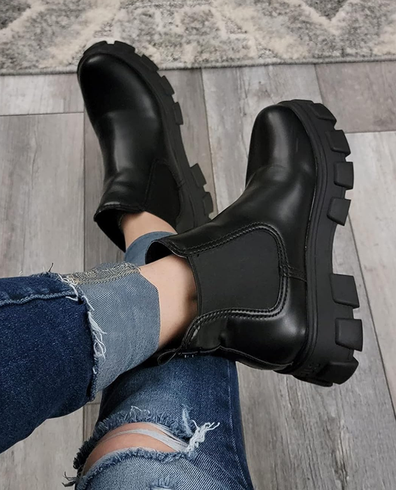 A reviewer wearing sleek black chunky boots