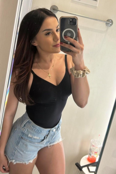 A reviewer modeling the black tank bodysuit with denim shorts