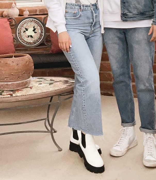 A reviewer modeling white and black boots