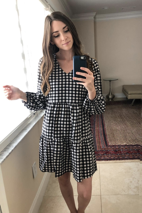 A reviewer models the black and white gingham dress, showcasing its timeless charm