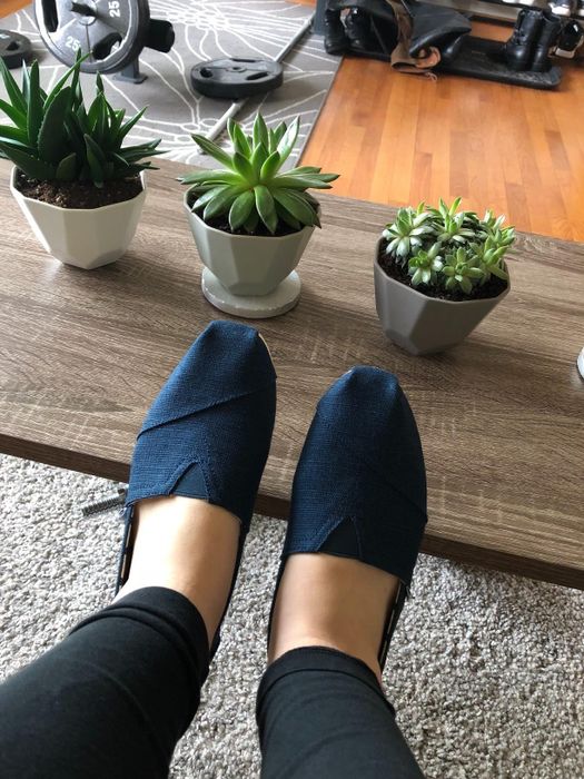 A reviewer wearing blue Toms slip-ons