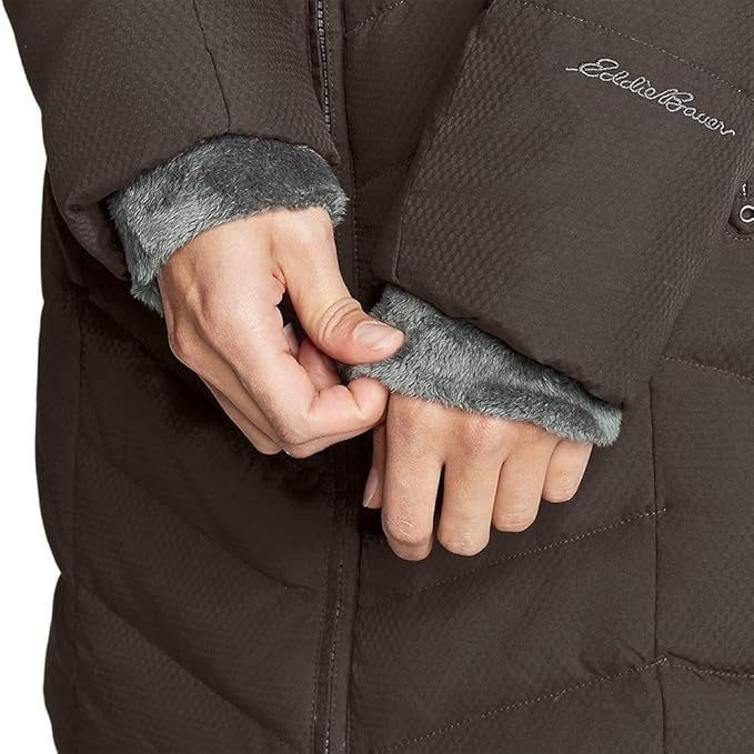 A person adjusts the sleeve cuffs of their winter coat, showcasing the faux fur lining that adds both warmth and style.