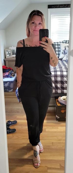 Reviewer showcasing the black off-the-shoulder jumpsuit