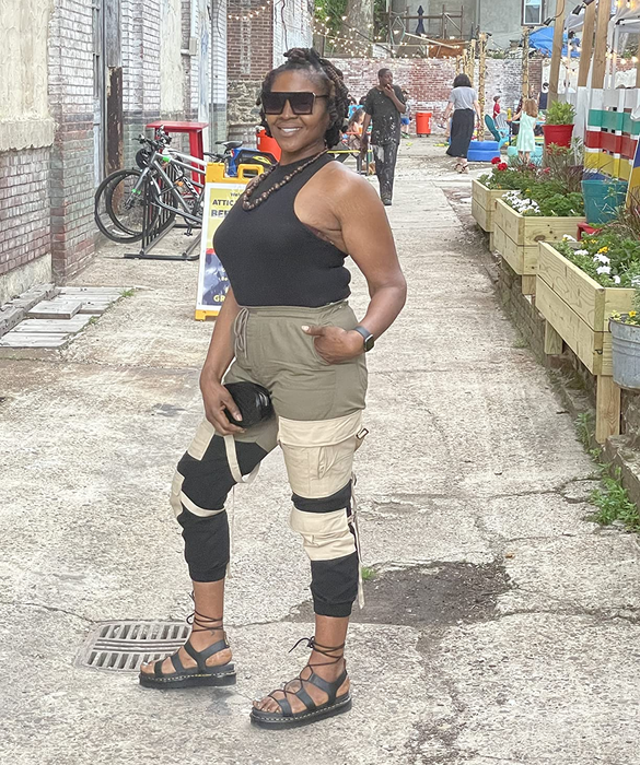 A reviewer strikes a confident pose on the street, wearing sleek black sandals