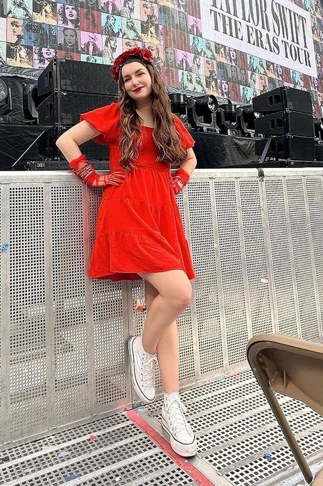 another reviewer in a red dress paired with white sneakers, standing at a concert venue with a