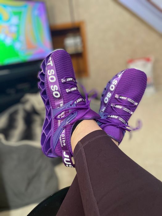 A reviewer sporting purple athletic shoes with bold text detailing