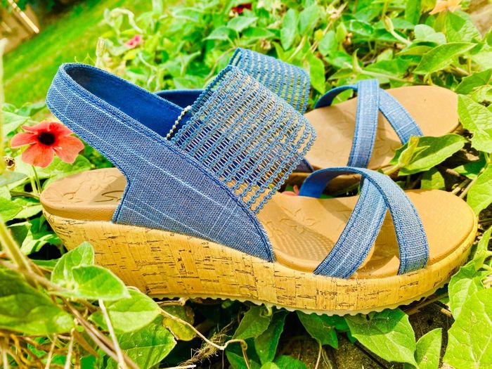 A pair of wedge sandals featuring vibrant blue straps