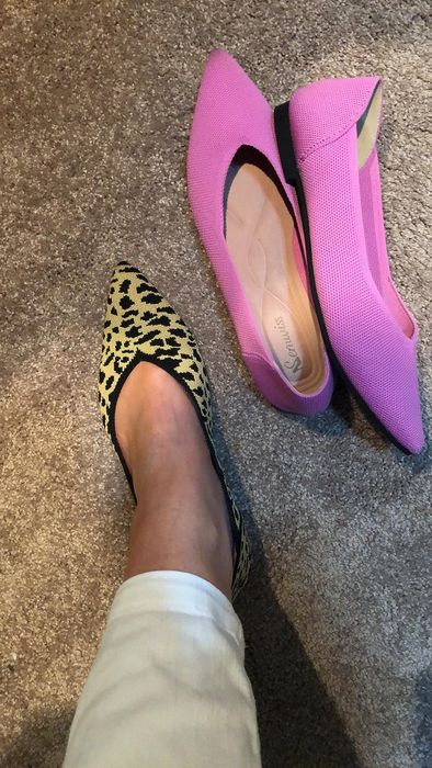 A reviewer trying on leopard print flats alongside a pair of pink flats