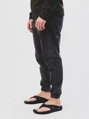 A person wearing black pants and sandals, standing with their hands visible, possibly showcasing a casual look suited for a shopping-related article.