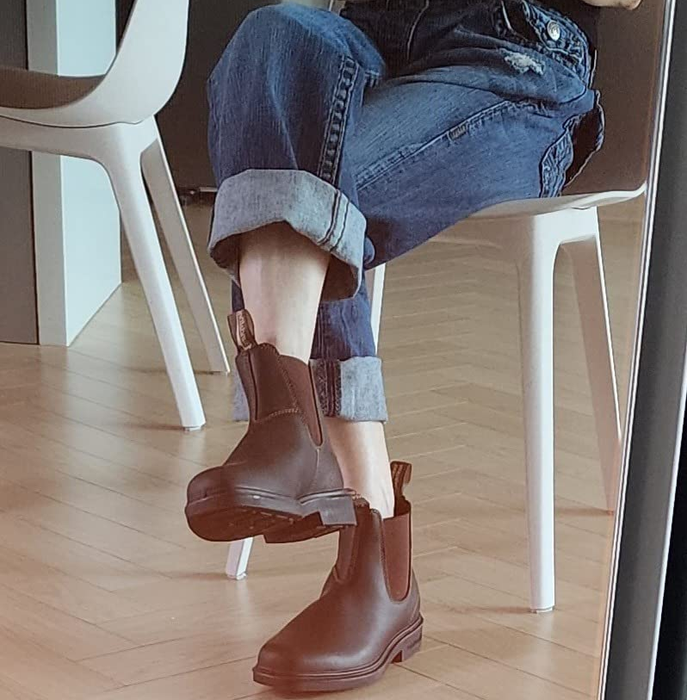 A reviewer seated while wearing brown ankle boots