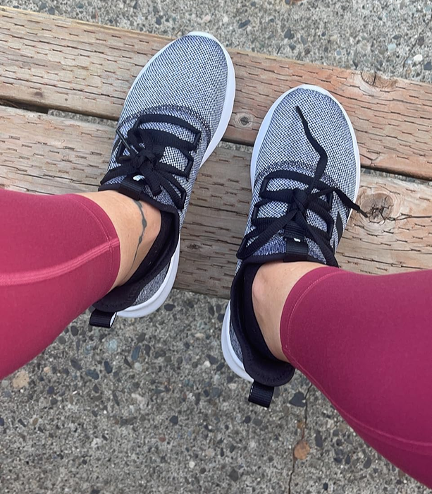 A reviewer wearing gray sneakers with black laces
