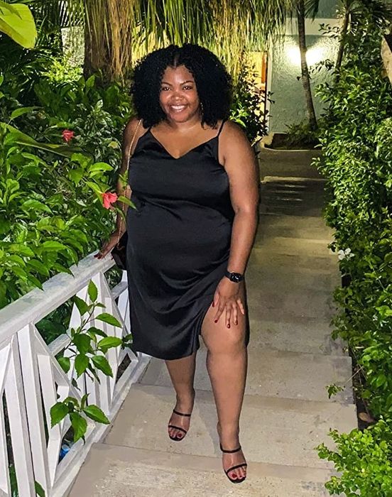 A reviewer models a black dress complemented by strappy sandals