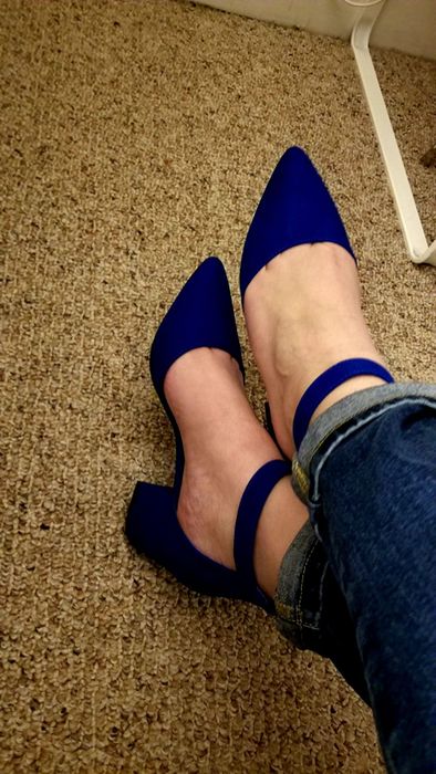 A detailed shot of crossed legs wearing blue pointed-toe heels with ankle straps