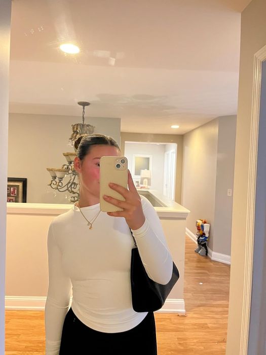A reviewer modeling the white long-sleeve top