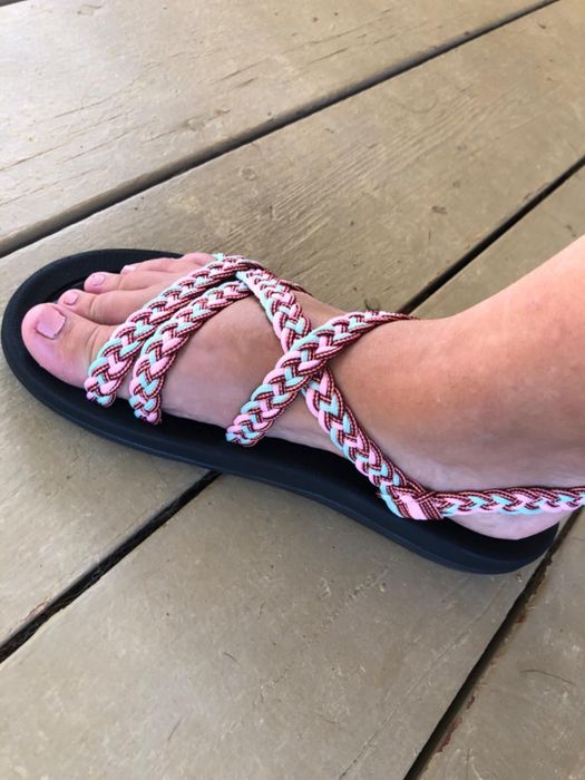 A reviewer wearing sandals with vibrant, braided straps