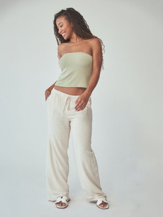 A person styled in a strapless top and wide-leg pants, posing casually for a fashion feature