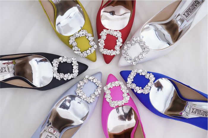 Seven pairs of sophisticated high-heeled shoes in various hues, each adorned with sparkling buckle details, arranged in a circular display