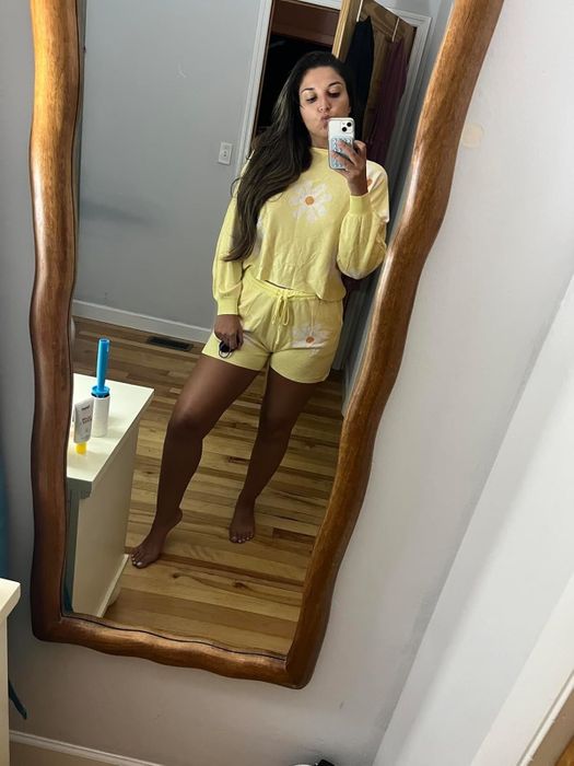 A reviewer takes a mirror selfie, wearing a casual yellow matching top and shorts set with a floral design