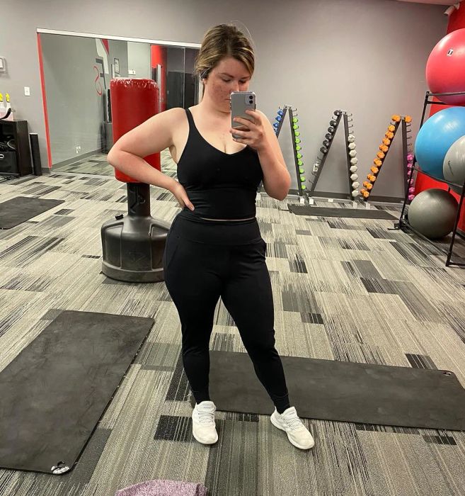 a reviewer capturing a mirror selfie at the gym in the black joggers