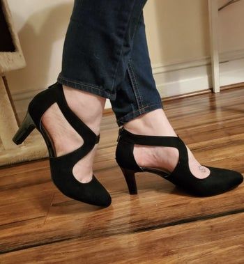 A reviewer showcasing black pumps