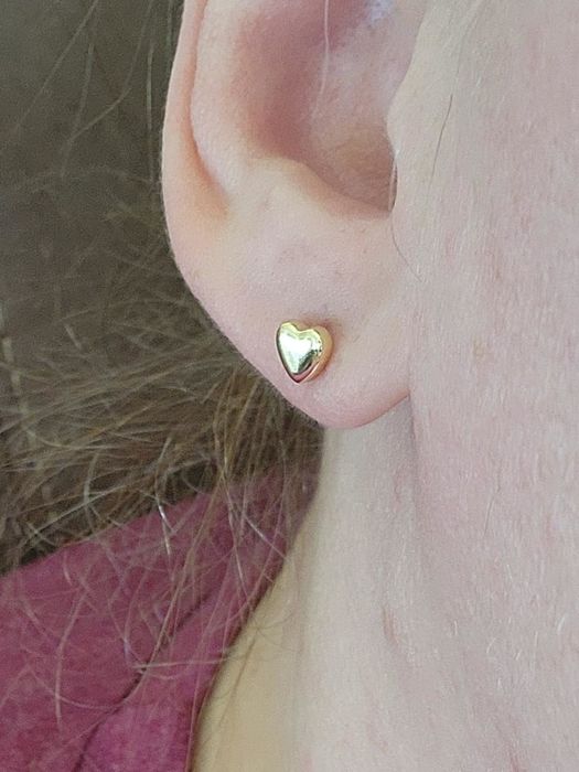 A reviewer showcasing the yellow gold heart earrings