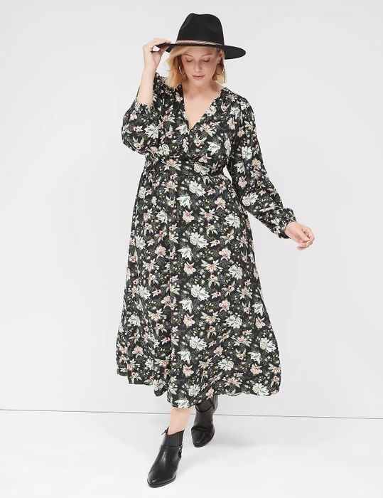 model in a floral dress, black hat, and ankle boots posing against a plain background
