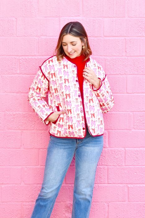 model showcasing a white barn jacket adorned with red and pink bows and red trim