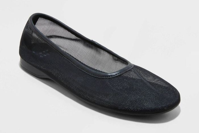 A black slip-on ballet flat featuring a sheer mesh design, offering a lightweight and fashionable appearance