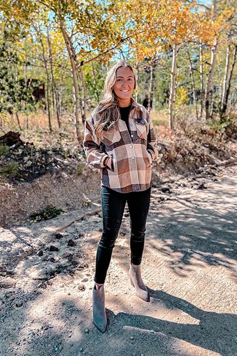 reviewer in a tan plaid shacket, partially buttoned with hands in the pockets