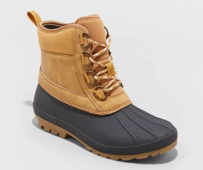 A tan and black winter boot featuring a lace-up front, durable sole, and classic duck boot design, ideal for cold and wet weather