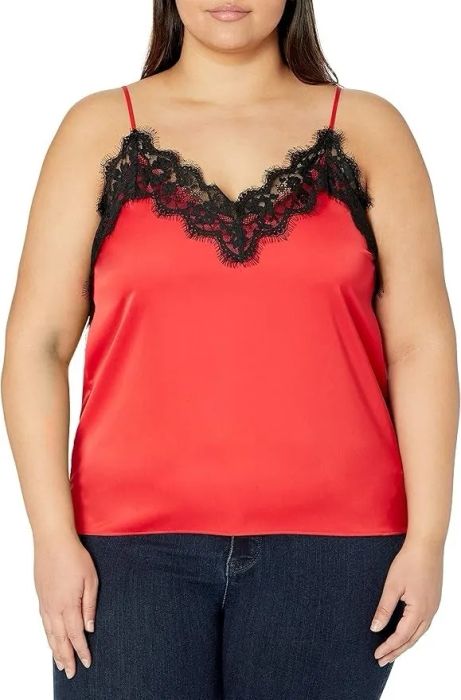 A person models a chic red satin camisole featuring black lace trim, styled with dark jeans for a trendy, casual outfit