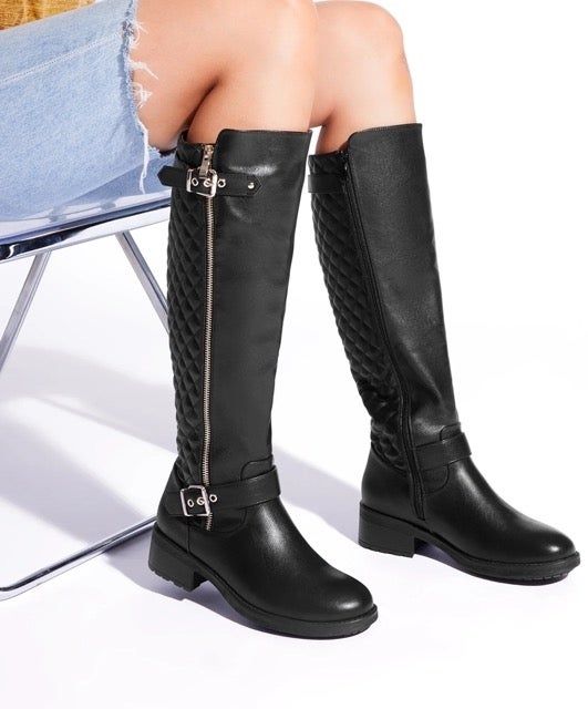 A close-up shot of a model seated in a chair, showcasing the boots