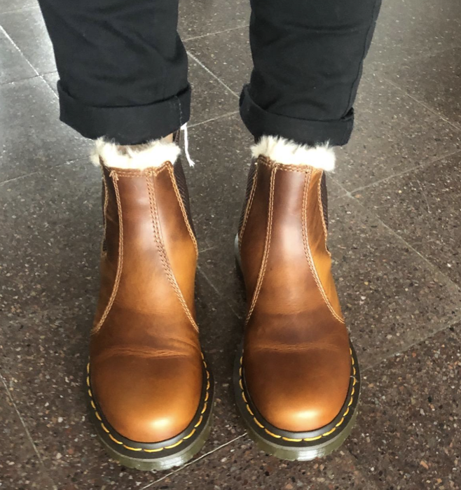A reviewer shows off their brown boots in a casual setting.