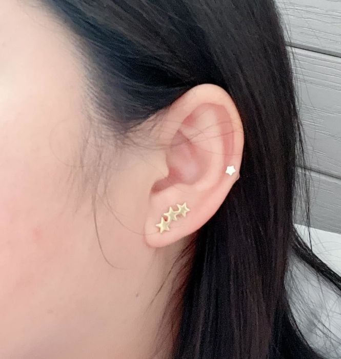 A reviewer modeling the yellow gold star earrings