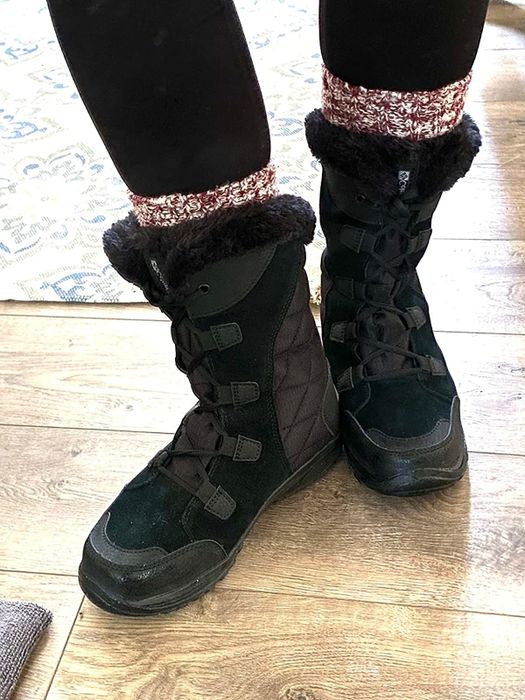A reviewer wearing black snow boots, showcasing their winter-ready footwear.