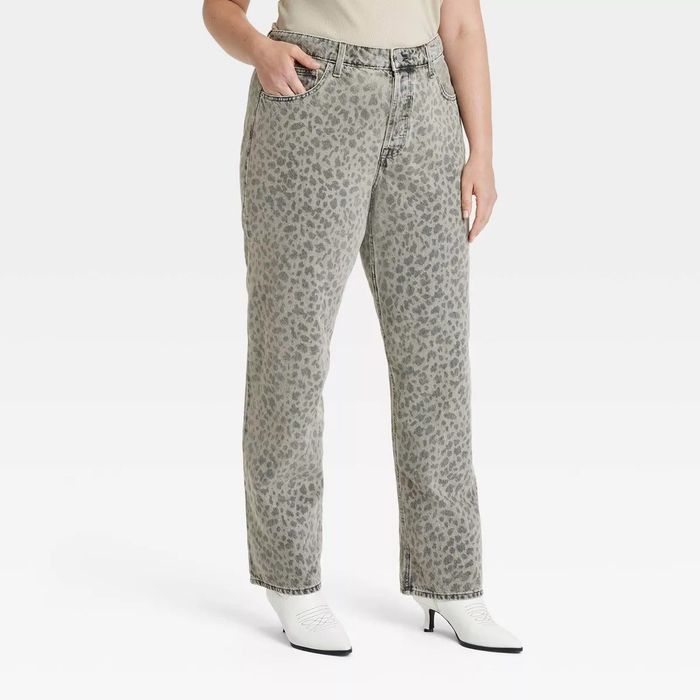 Model showcasing leopard-print high-waisted jeans paired with white heeled ankle boots against a neutral backdrop