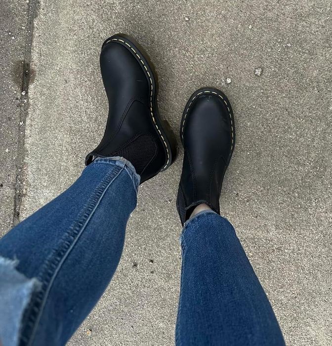 A person rocking skinny jeans and black Chelsea boots on a concrete surface