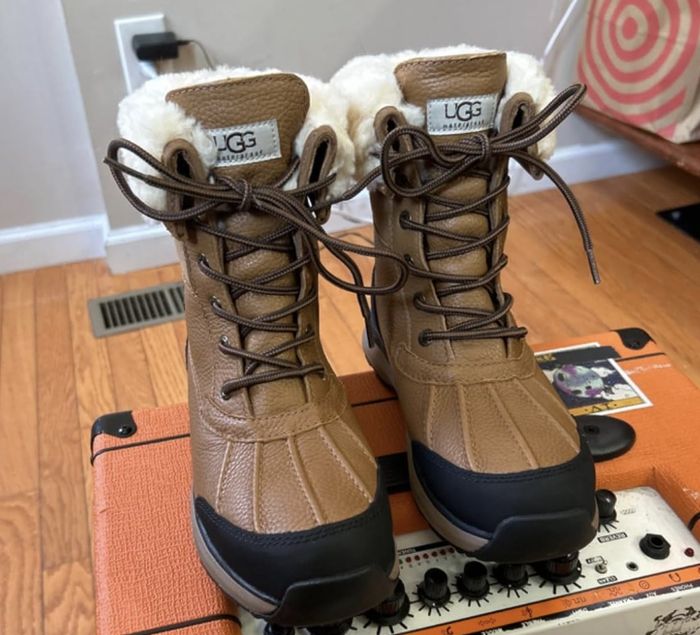 UGG winter boots with fur lining and a lace-up design, displayed on a music amplifier indoors.