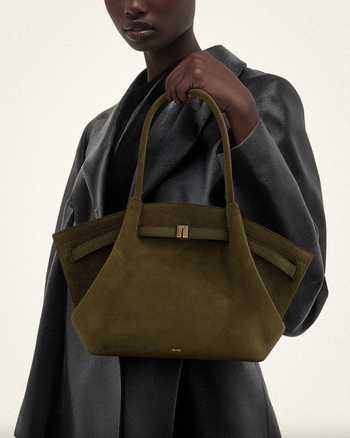 Model holding a sleek suede handbag with a structured design, styled in an elegant outfit ideal for a chic shopping ensemble