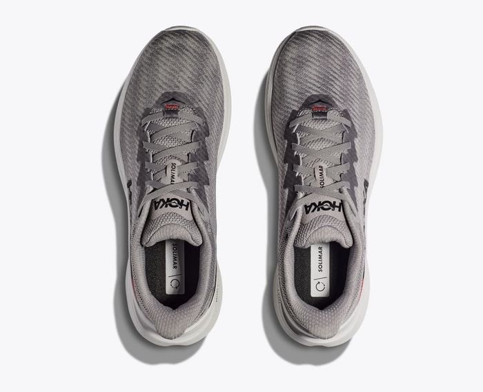 A top-down view of a pair of HOKA running shoes showcasing visible laces and a mesh design.