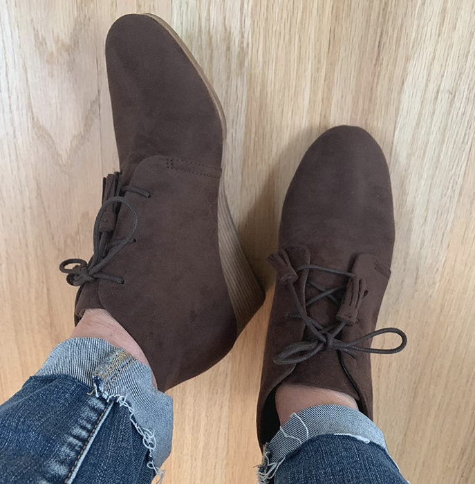 A reviewer wearing dark gray lace-up wedge boots.