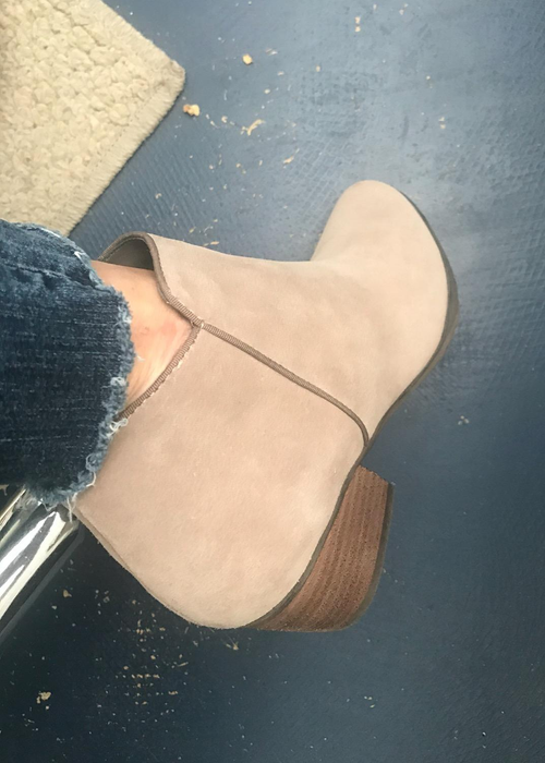 A reviewer wearing boots in the sand suede color.