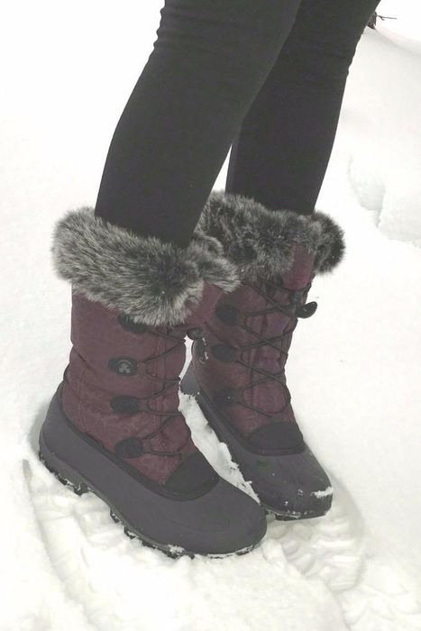 A reviewer standing in the snow, wearing dark red fur-lined winter boots, leaving footprints in the snow.