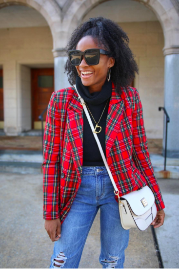 A reviewer styling the red and green plaid blazer open over a turtleneck and ripped jeans