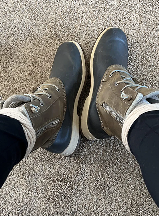 A reviewer wearing boots that combine brown and black, showing off their rugged look.