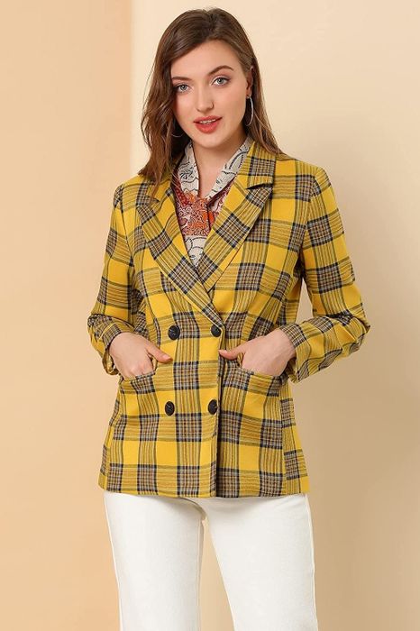 A model wearing the yellow plaid blazer closed, hands tucked into the pockets